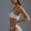 Oh Polly Bademode: HOTFIX Edition verziertes Ein-Schulter-Bandeau-Bikinioberteil in Weiß Oh Polly Bademode: HOTFIX Edition verziertes Ein-Schulter-Bandeau-Bikinioberteil in Weiß